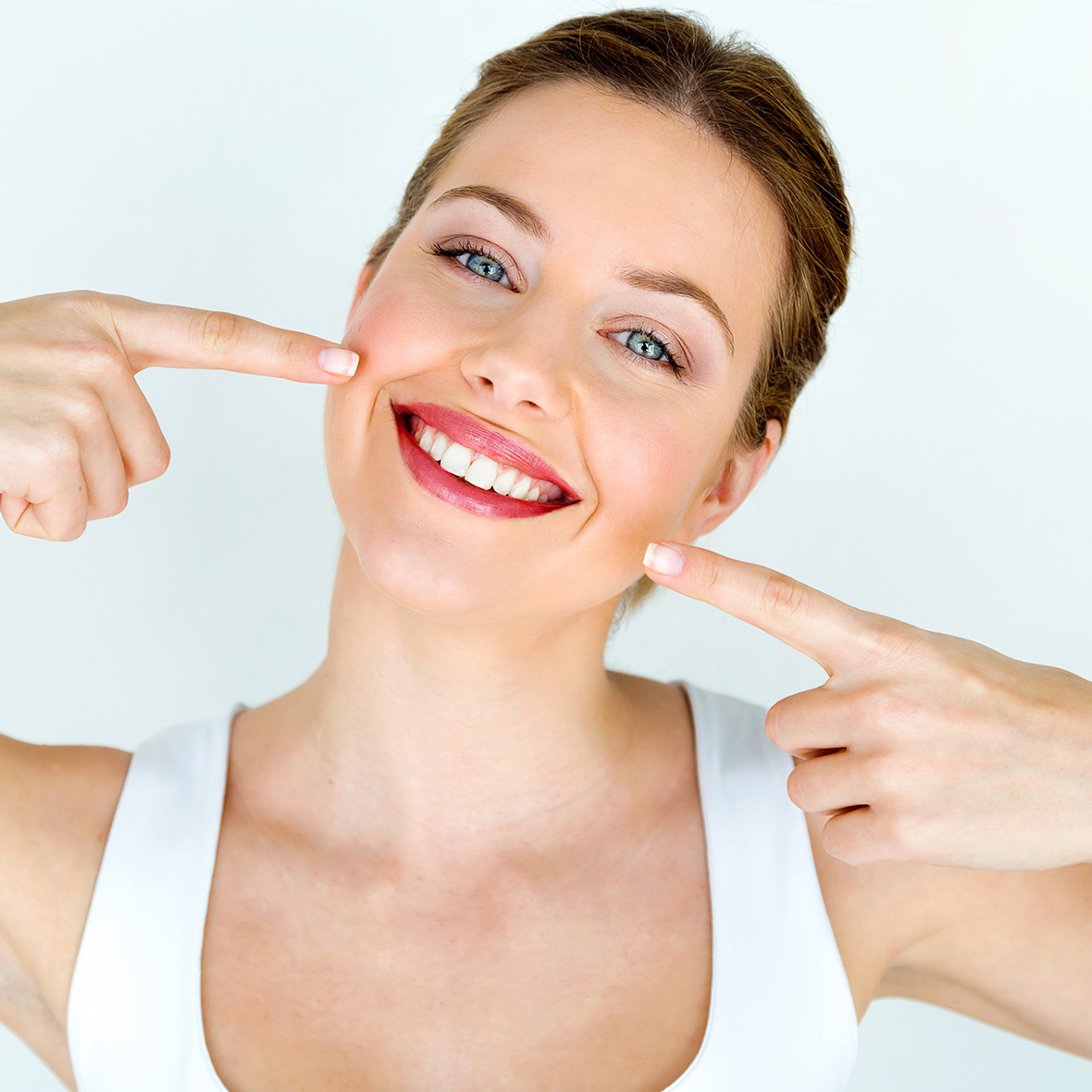Egy fiatal lány mutat a tökéletesen fehér fogsorára a fogkőleszedés után.